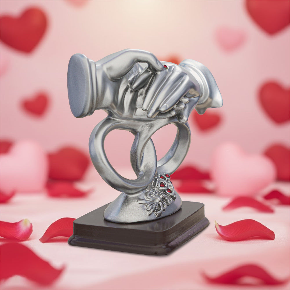 Silver trophy with hands holding a ring on a pink background with hearts and rose petals